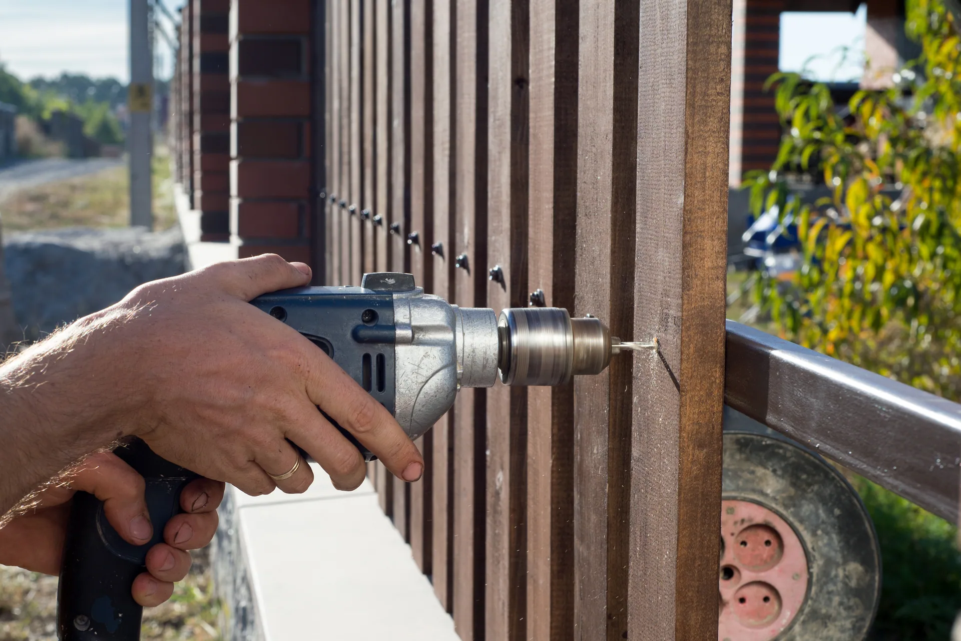 Power drill fastening wood fence slats brick posts