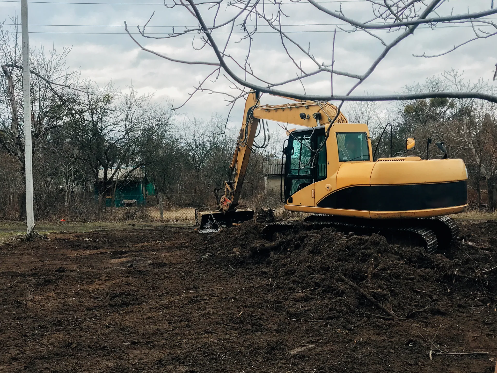 Yellow excavator mulching attachment cleared lot brush removal