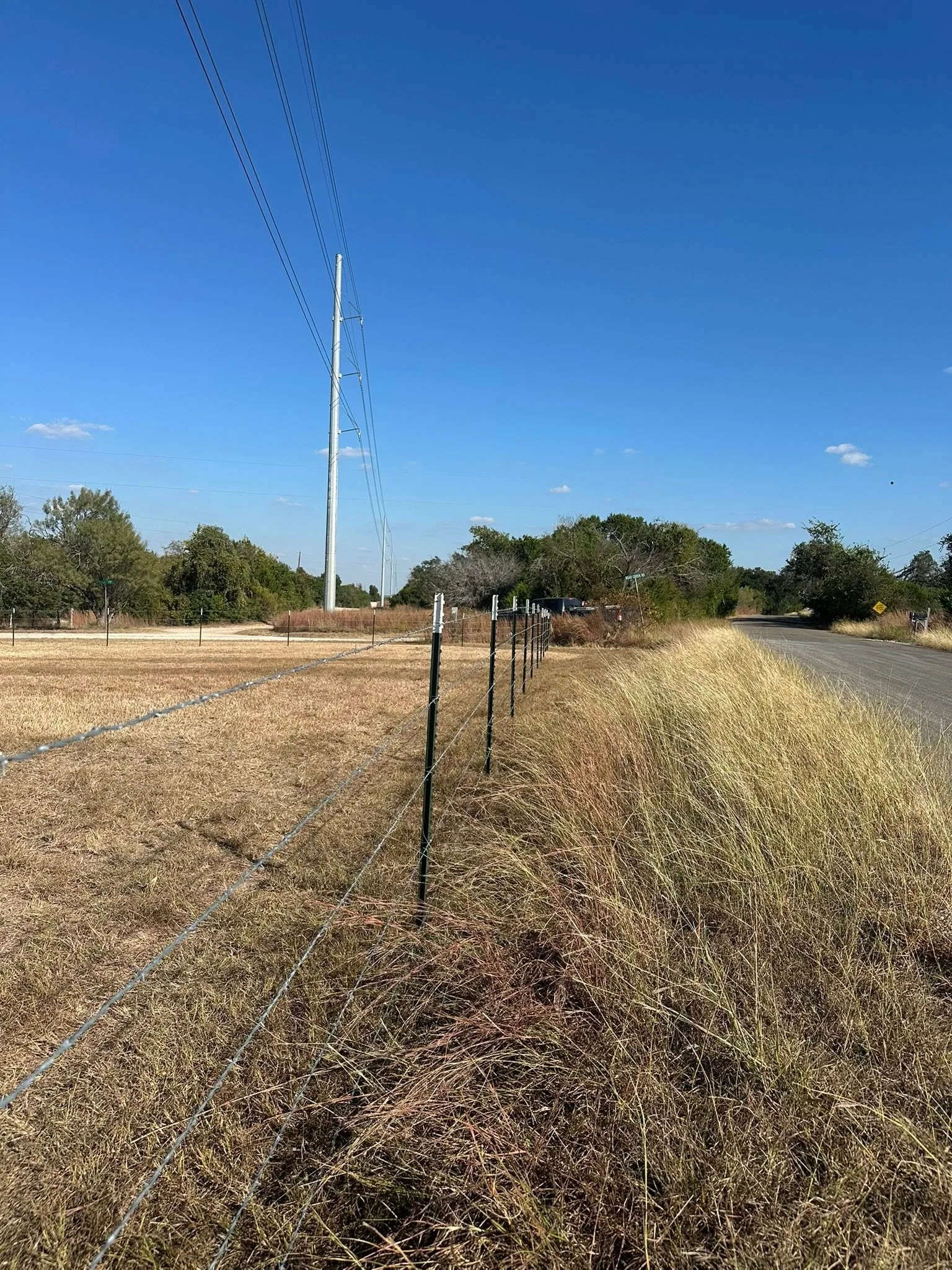 Barbed wire fence line steel posts rural road