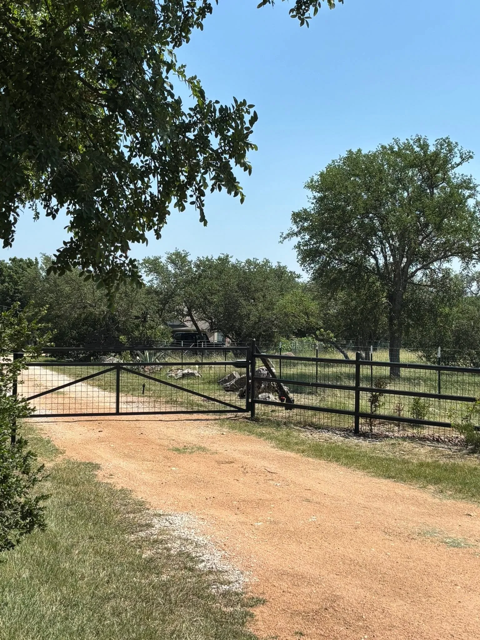Black steel driveway gate pipe rail fence red dirt drive texas