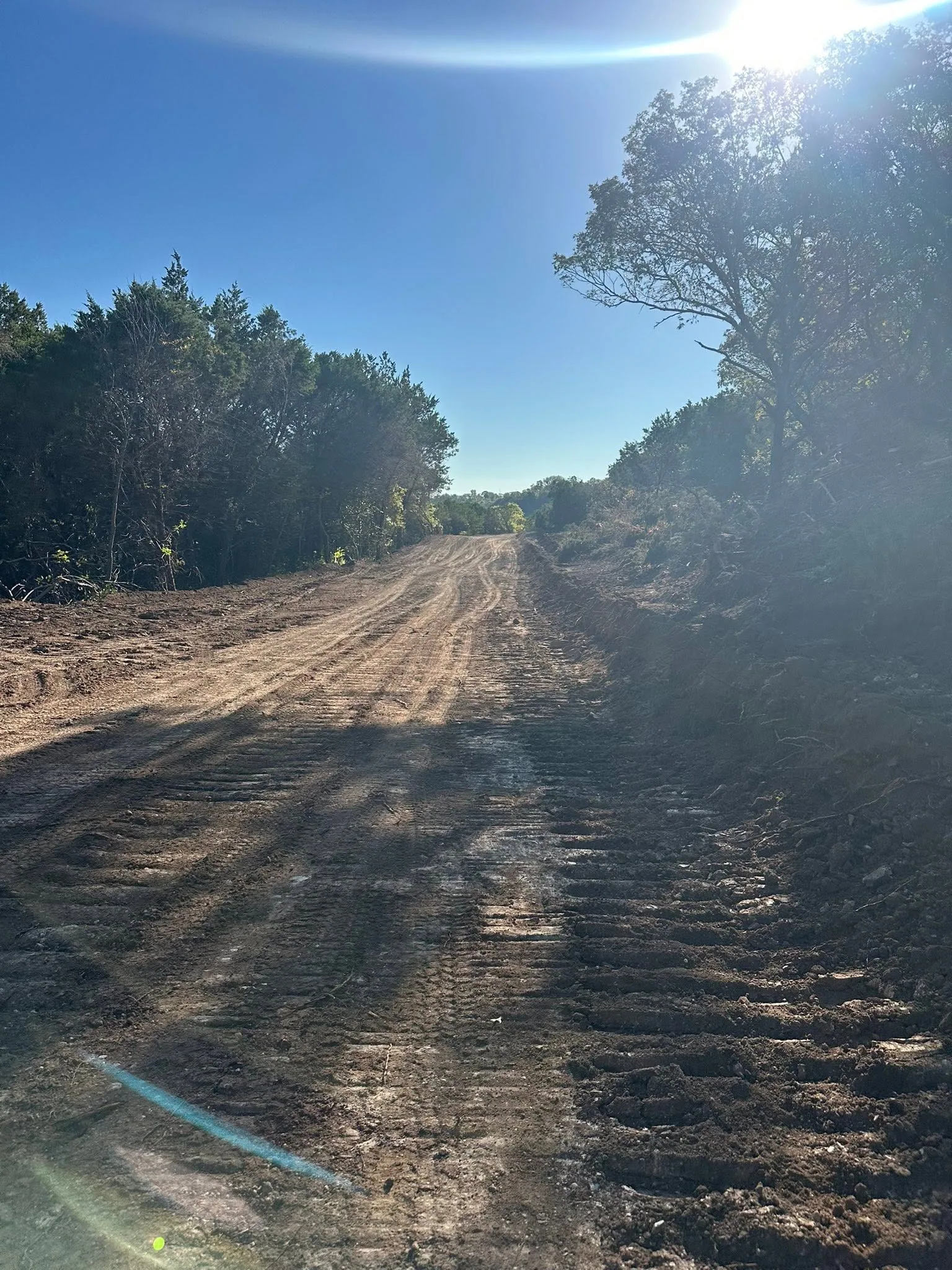 Fresh cut dirt access road track marks cedar oak hill country