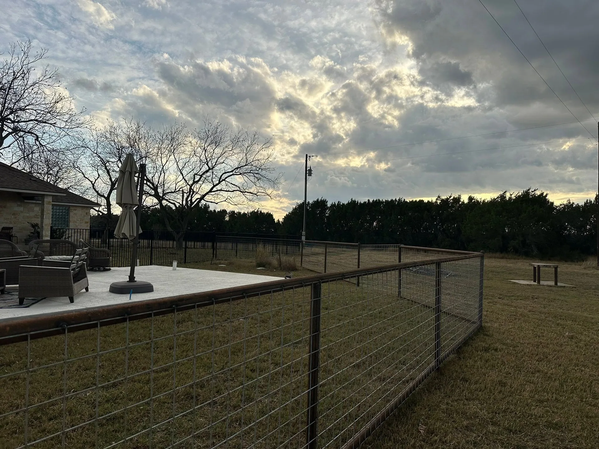 Hog panel yard fence pipe frame concrete patio dusk texas
