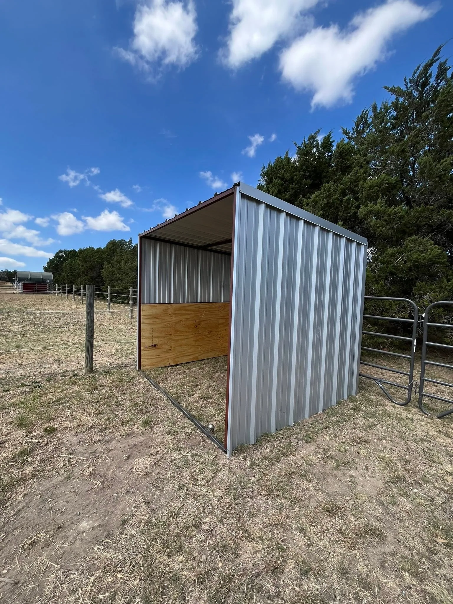 Open front metal loafing shed plywood wall pasture cedar trees texas