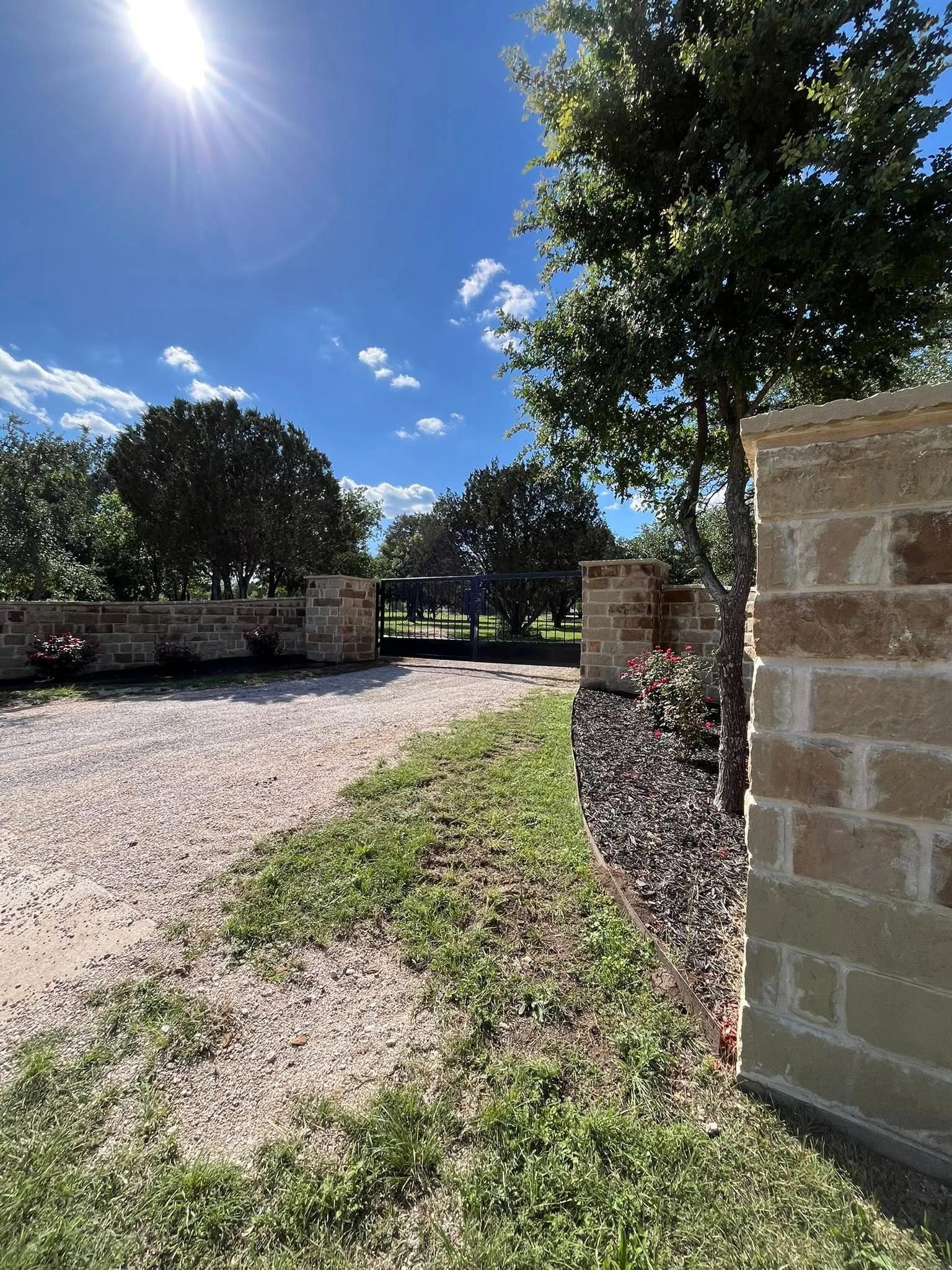 Stone column entry wall closed blue driveway gate gravel drive central texas