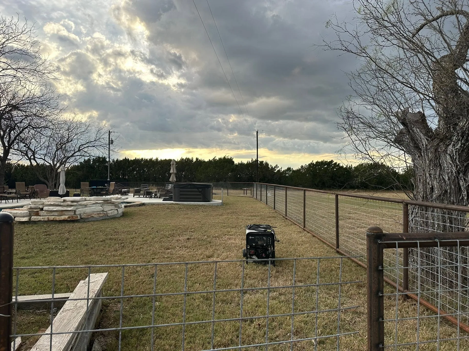 Welded pipe frame wire panel fence backyard patio hot tub dusk
