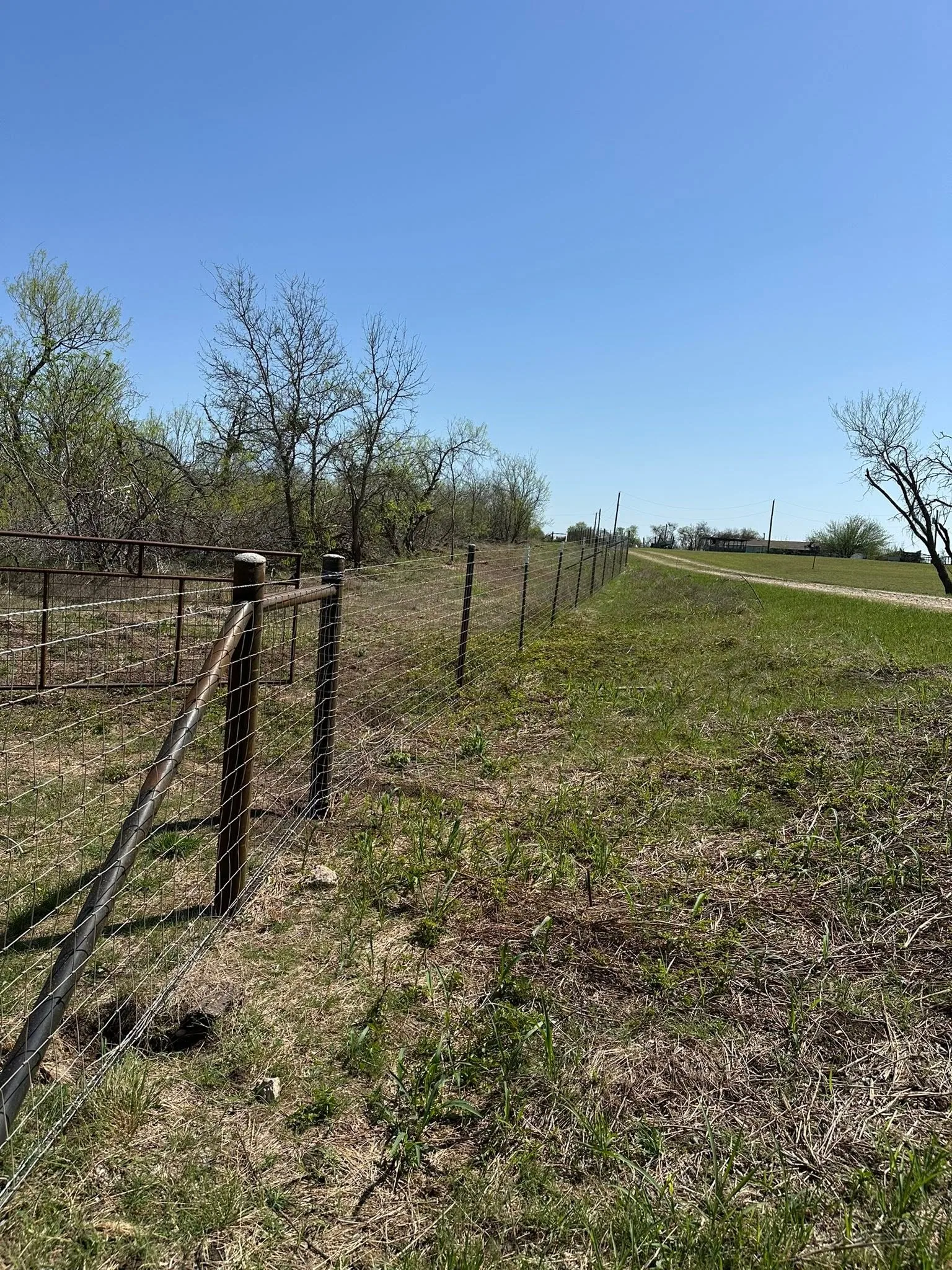 Wood corner post diagonal brace woven wire fence grass roadside texas